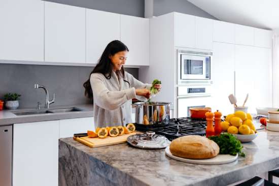 A woman cooking healthy food in her kitchen and smiling