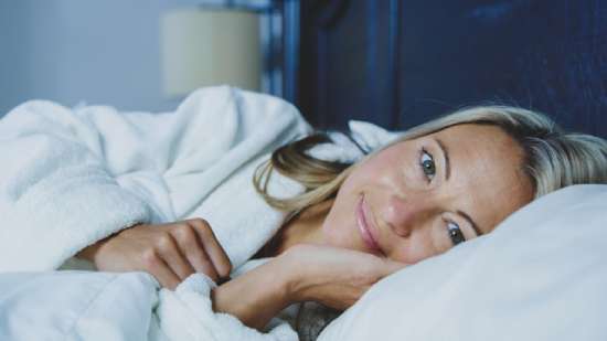 A woman relaxing in bed and smiling