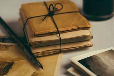 Parchment books tied in black ribbon, next to fountain ink pen and pictures of nature - AAAF