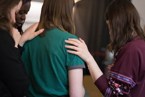 Adventist school staff gathered around a student who has made mistake, praying for her as part of redemptive discipline