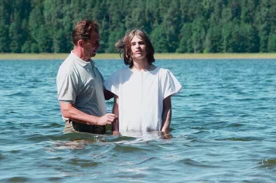 A man baptizing a boy in a river, just as John the Baptist baptized people in the Jordan River