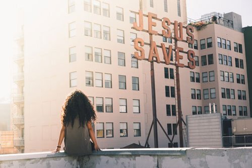 Girl sitting on the terrace looking at the signboard which says Jesus Saves showing how Adventists value evangelism