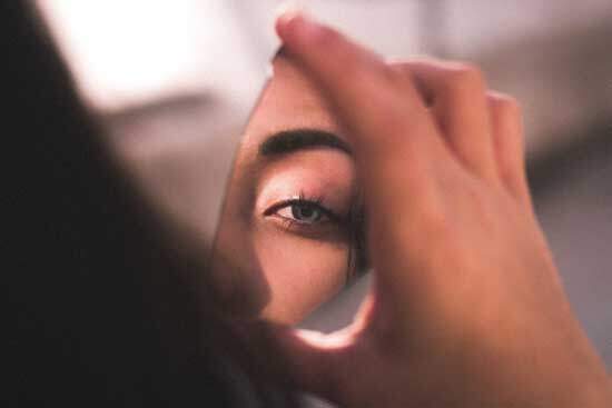 A woman looking at her reflection in a broken piece of glass, reminding us that we're all broken because of Adam and Eve's fall into sin