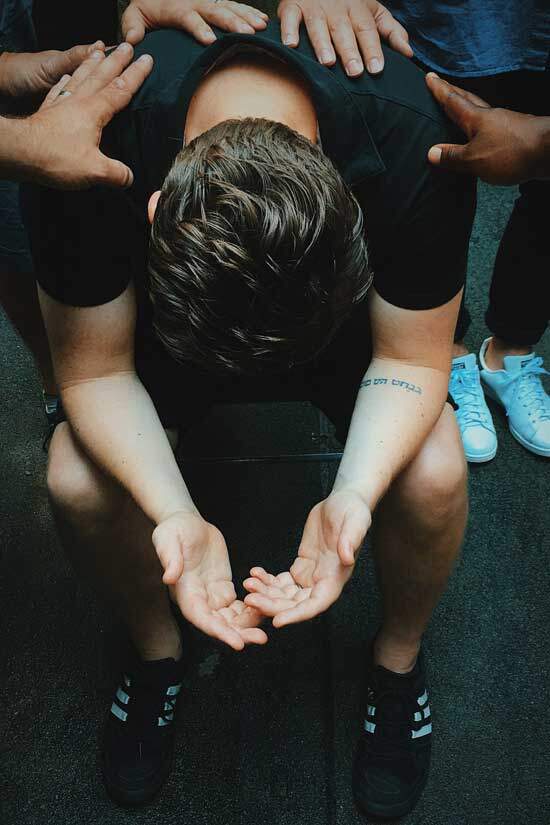 People praying over a man just as members of the early Christian church prayed over one another