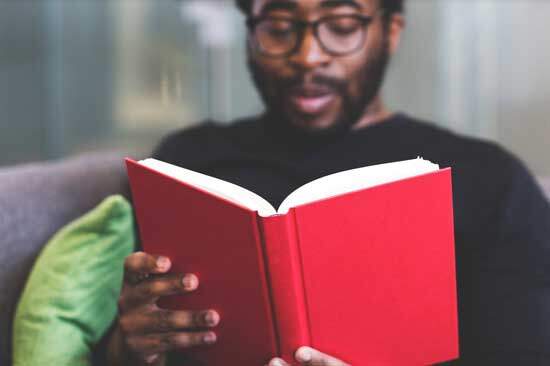 Man reading a red book of Ellen White as Adventists believe her writings called lesser light are important to our faith