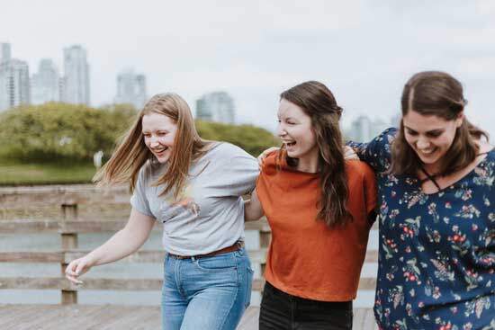 Three girls with their arms around each other, laughing, to remind us of the New Jerusalem where all tears and sorrow will be wiped away