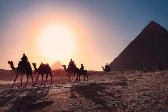 Travelers on camels near pyramids and sun shinning across the horizon as we learn about deliverance of Israelites from Egypt