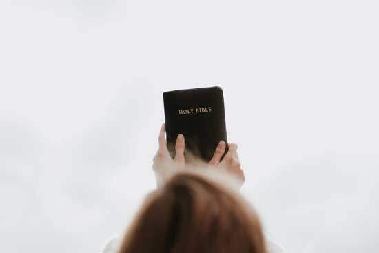 A woman lifting a Bible up to the sky