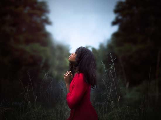 Woman praying in nature as we learn the importance of private prayers and time alone with God to pour our hearts to Him
