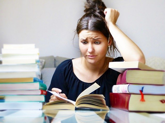 Woman reading books, as she is worried for her exam and we learn how worry pushes us to overcome challenges.