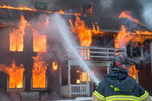 A firefighter spraying water on a burning house, a loss of a possession
