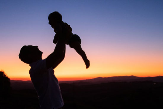 Silhouette of a father holding his child as we learn how God cares for us more dearly than parents care for their children.