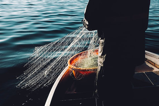 Fisherman at sea with net fishing as we learn that Simon Peter and his brother Andrew, disciples of Jesus, were fishermen.