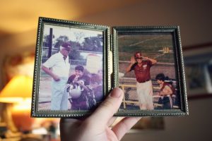 A hand holding a picture frame and looking at photos of a deceased family member