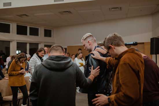 People praying over a man as we are called in our ordinary nature to do extraordinary work in sharing Gospel of Jesus Christ.