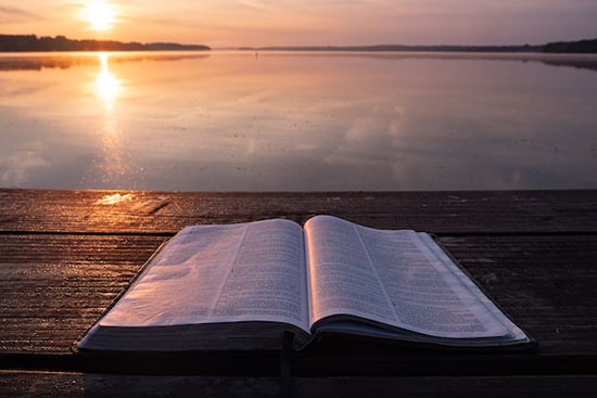 A Bible open with a sunset in the distance