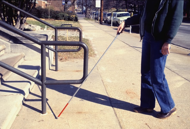 A blind person using a cane to walk