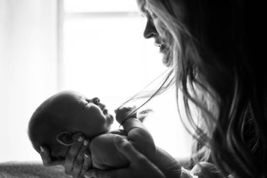 A woman holding a baby and looking into its face