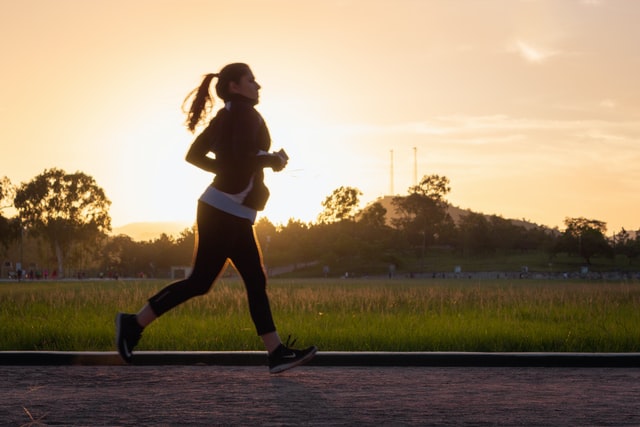 A woman jogging in the light of the rising sun to care for her health