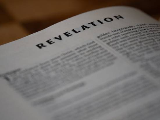 A Bible is open to the book of Revelation.