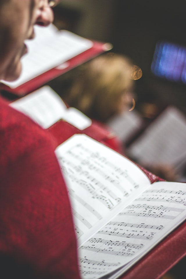 A man holding a hymnal and singing from it