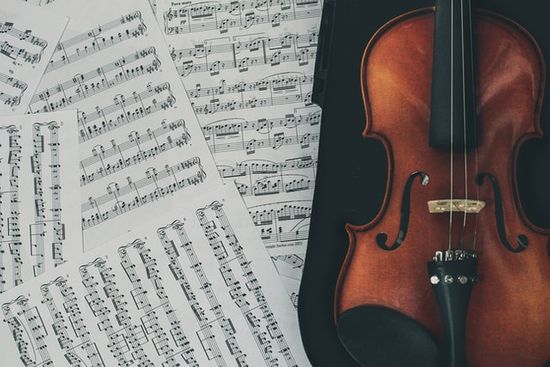 A violin laid next to scattered sheet music