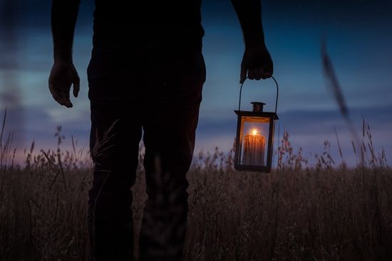 A person holding lamp in a dark night as we study how Great Disappointment pushed some believers back to study of Scriptures.