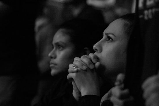 Women praying with folded hands and open eyes as we study how Great Disappointment led Ellen White to further study of Bible.