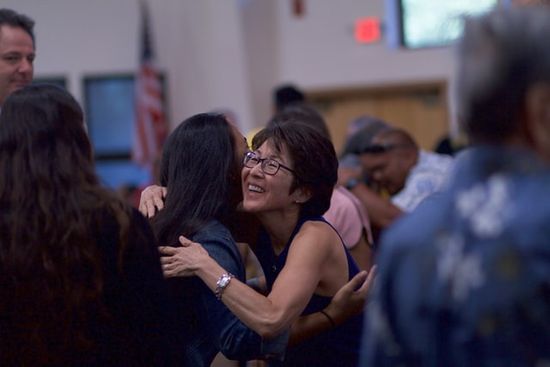 Two women hugging in Church as we learn how Sabbath School is for all people of all ages, to connect and study the Bible.