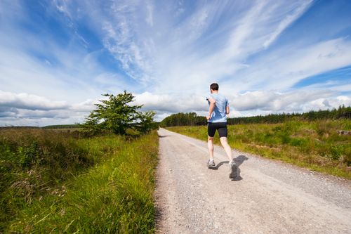 Man jogging down a road in the country, following the health principles of exercise and fresh air.