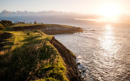 Green-fields near seashore and sun rise at the horizon as we learn that Adventists believe in literal six-day creation.