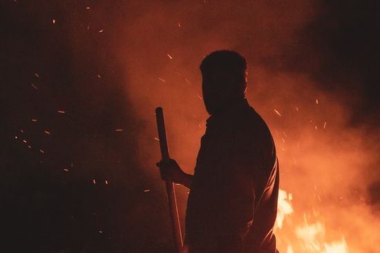 Moses with a staff in hand turning to look at the burning bush