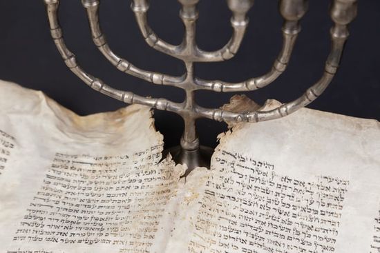 A seven-branched candlestick next to Hebrew scrolls of the Bible