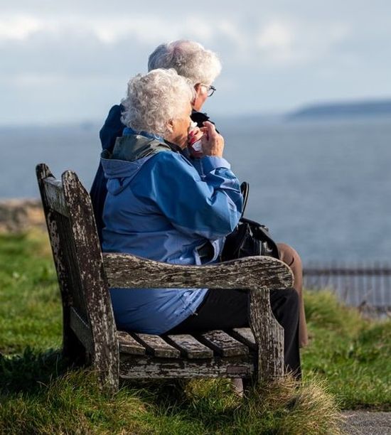 Elderly Couple Outdoors An elderly couple sitting outdoors by a lake as they enjoy the long life resulting from their healthy lifestyle