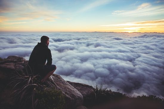 A man on a hill watching clouds in a valley and contemplating God's plan for his life