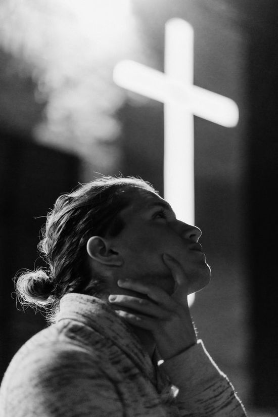 A woman looking up with a white cross behind her as she remembers the blessed hope of Jesus' second advent