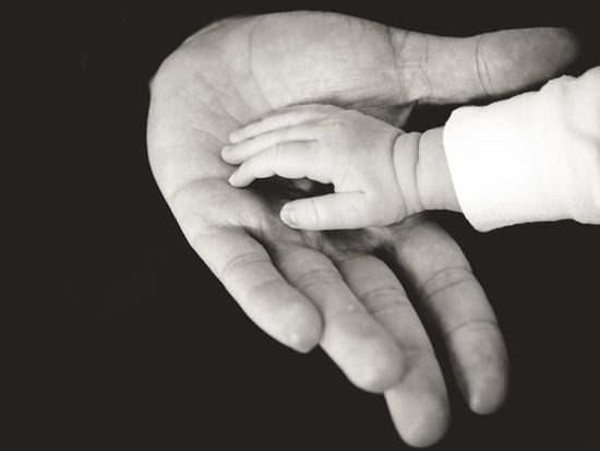 A child's hand in a parent's hand, illustrating how we can trust God