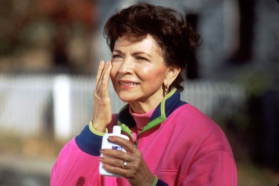 A woman applying sunscreen to her face