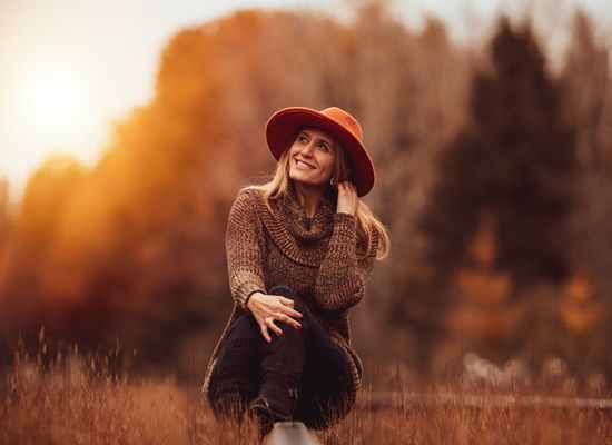 A woman sitting in a field at sunset, getting the last bit of sunshine