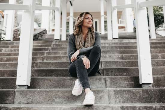 A woman sitting on the steps in front of a building and enjoying the sunlight