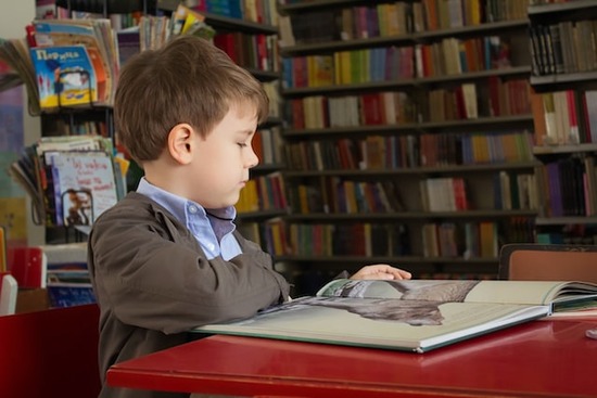 A little boy reading a children's Bible story book from an Adventist Book Center