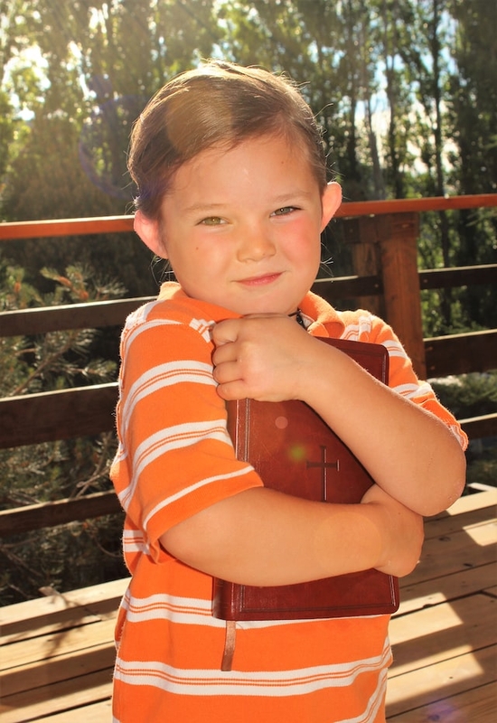 A little boy hugging a Bible