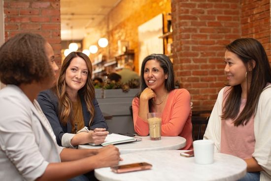 A group of women sitting at a table and having a Bible study at a church workshop