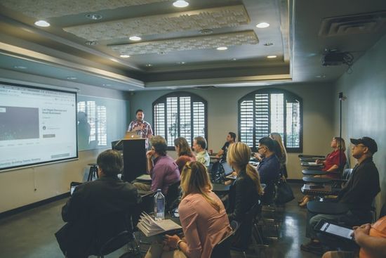 A man gives a presentation in classroom A man gives a presentation in front of a small audience.