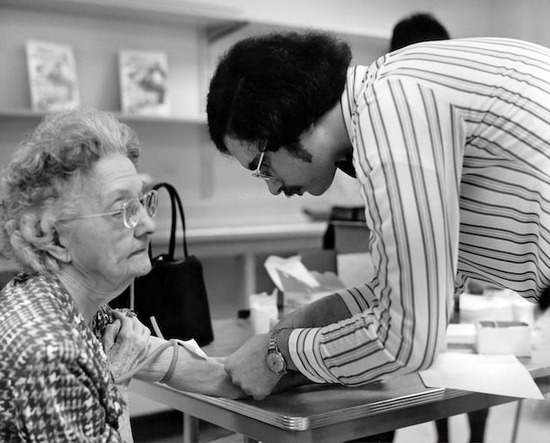 A scientist drawing the blood of a woman in a study to improve medical practices