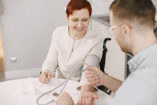 Doctor taking woman's blood pressure A doctor takes a woman's blood pressure, illustrating how lower blood pressure is one of the benefits of the vegetarian diet.