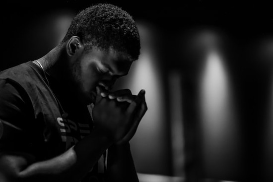 man with head bowed in prayer for God's forgiveness