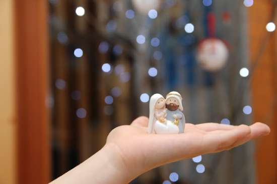 A child holding small figurines of Mary, Joseph, and Jesus from a Christmas nativity scene
