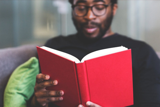 A man reading a book with a red cover