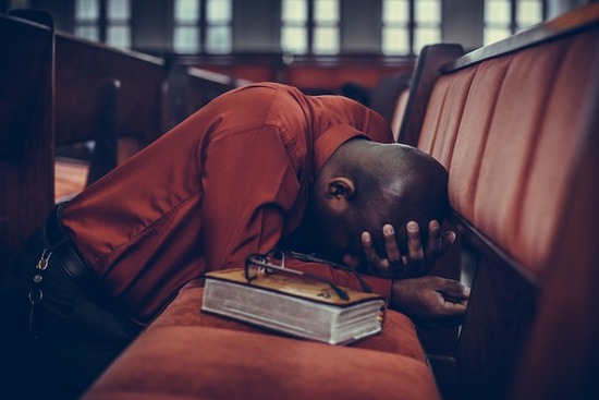 Man kneeling down at a Church pew, earnestly praying as we explore what is the importance of prayer in our lives